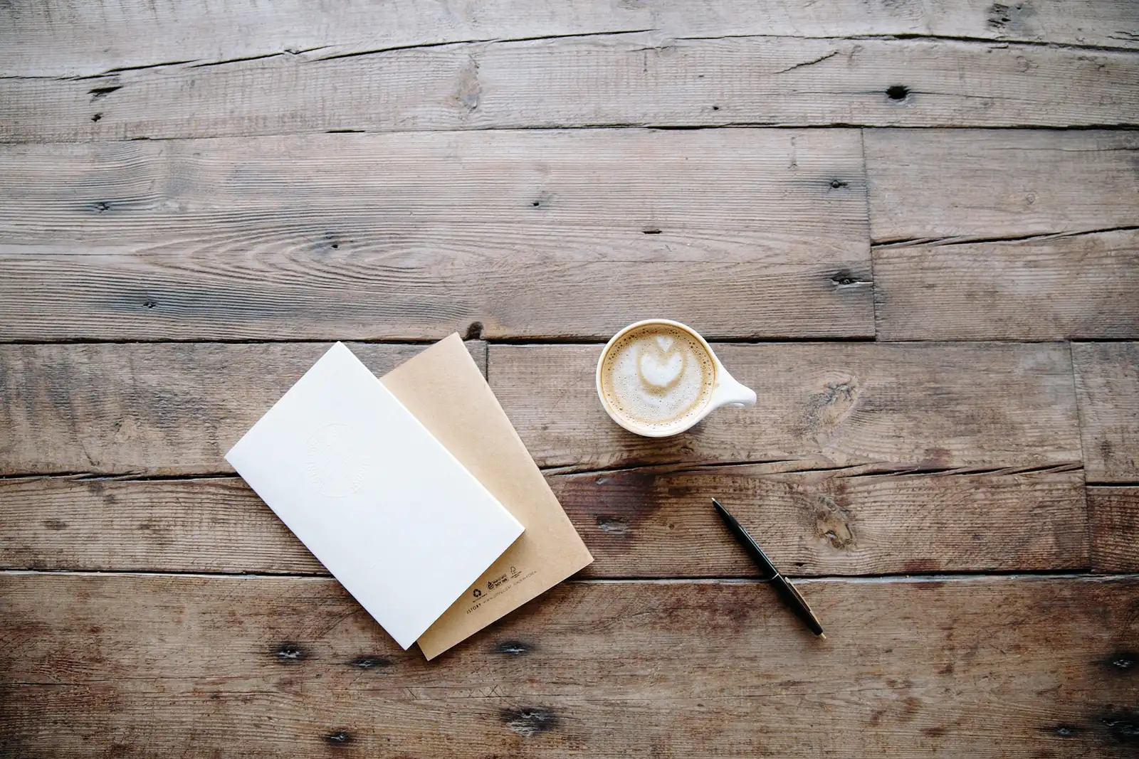 An open journal, pen and cup of coffee on a wooden table